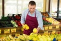 Male seller of vegetable department of store replenishing showcase with apple, put ones on showcase Royalty Free Stock Photo