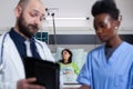 Practitioner doctor with black nurse checking recovery treatment using tablet computer Royalty Free Stock Photo