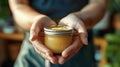 A practitioners calloused hands holding a jar of herbal salve used to treat a variety of ailments and injuries