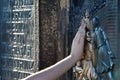 Tourist hand touches a bronze bas-relief of Jan Nepomuk on the Charles Bridge