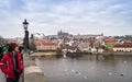 Prague, Bohemia / Czech Republic - November 2017: tourists walking on the Charles bridge with view on Prague castle and Vltava riv