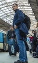 A guy waiting for the train at the Prague main train station with people boarding the blue train of Ceske Drahy