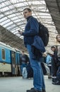 A guy waiting for the train at the Prague main train station with people boarding the blue train of Ceske Drahy