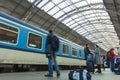 A guy waiting for the train at the Prague main train station with people boarding the blue train of Ceske Drahy