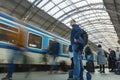 A guy waiting for the train at the Prague main train station with people boarding the blue train of Ceske Drahy