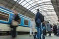 A guy waiting for the train at the Prague main train station with people boarding the blue train of Ceske Drahy