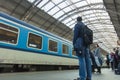 A guy waiting for the train at the Prague main train station with people boarding the blue train of Ceske Drahy