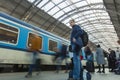 A guy waiting for the train at the Prague main train station with people boarding the blue train of Ceske Drahy