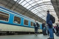 A guy waiting for the train at the Prague main train station with people boarding the blue train of Ceske Drahy