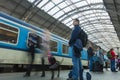 A guy waiting for the train at the Prague main train station with people boarding the blue train of Ceske Drahy