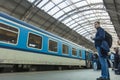 A guy waiting for the train at the Prague main train station with people boarding the blue train of Ceske Drahy