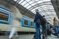 A guy waiting for the train at the Prague main train station with people boarding the blue train of Ceske Drahy