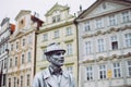 Prague, Czech Republic - August 17, 2019: Gray living statue of a man in the hat against historical facades of Old City Square