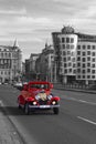 PRAGUE, CZECH REPUBLIC, JANUARY 1: The world famous Dancing House, a modern building and red retro-mobile with tourists on the br Royalty Free Stock Photo