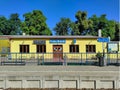 A vibrant view of Brank train station\'s yellow facade and blue label