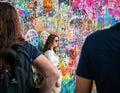 Young girl tourist having a picture taken at the Lennon Wall in Prague