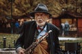 Prague, Czech Republic/ 1 November 2019: Old street musician with sax playing on the street, close up portrait. Tourist attraction