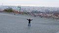 Empty Hradcanske Namesti square on a cold autumn morning, with a lonely person stretching out hands