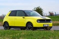 Prague, Czech republic - October 02, 2020. Yellow green electric Honda E - driving between green fields