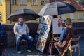 PRAGUE, CZECH REPUBLIC - OKTOBER 10, 2018: Street artist paints a portrait of man under umbrella on bridge