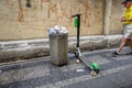 An electric scooter for hire parked next to an over flowing bin on a street in Prague