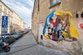 Graffiti by Chemis artist depicts a little girl hiding a European fairy tale character under a blanket from Ukrainian flag