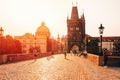 Prague, sunrise over Charles Bridge with tourist walking through.