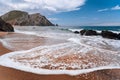 Praia da Adraga at atlantic ocean, Portugal. Foamy wave at sandy beach with picturesque landscape background Royalty Free Stock Photo