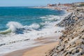 Selective focus of a wave on sand with a stone wall on Olinda beach with PÃÂ³voa de Varzim architecture breaking in blur in the bac Royalty Free Stock Photo