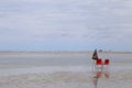 Two chairs and an umbrella on the sand on a deserted beach, with beige sand and blue mountain background. Cloudy sky in low light. Royalty Free Stock Photo