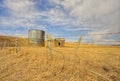 Prairie Landscape of Abandoned Shed and Grain Silo Behind a Barbed Wire Fence in Spring