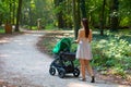 Woman pram walking side back view outside in the park