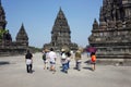 Group of Asian people with tour guide walking around ancient hindu Prambanan Temple complex