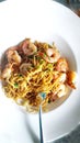 Prawn Chow & noodles in a white plate & spoon .