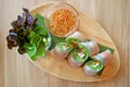 Prawn and fresh vegetable spring rolls served with green salad on a wooden plate