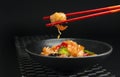 Prawn in red chopsticks on black background