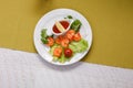 Prawns on skewers, grilled. served on lettuce leaves with cherry tomatoes, lemon and hot sauce. in a white round plate set on a Royalty Free Stock Photo
