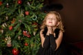 Pray a little girl in a black angel costume, looking with hope for peace. Happy childhood and peace. Christmas, New Year Royalty Free Stock Photo