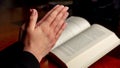Pray to God. Female hand in prayer over a Holy Bible, wooden table, close up view Royalty Free Stock Photo