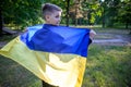 Pray for Ukraine. boy with Ukrainian flag running the summer park. Little kid waving national flag praying for peace. Happy child Royalty Free Stock Photo