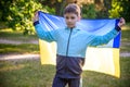 Pray for Ukraine. boy with Ukrainian flag running the summer park. Little kid waving national flag praying for peace. Happy child Royalty Free Stock Photo