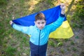 Pray for Ukraine. boy with Ukrainian flag running the summer park. Little kid waving national flag praying for peace. Happy child Royalty Free Stock Photo