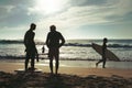 PRAYA GRANDE, PORTUGAL - Aug 11, 2017: silhouettes of surfers standing and walking on seashore in a sunny summer day