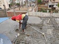 Poor labor workers are employed in a local household construction work. Iron rods are tied together before pouring concrete mixtur