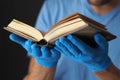 Prayer book in men`s hands in blue medical gloves Royalty Free Stock Photo