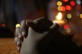 Prayer hands of a young girl on background of candle light and colorful Christmas bokeh lights. Person praying alone in silent. Royalty Free Stock Photo