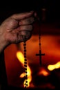 Prayer holding a crucifix or holy rosary beads, religion and praying, fire background