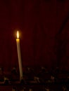 Prayer. Single church candle burns in front of red curtain. Memo