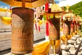 Buddhist prayer wheels in front of the temple jade-gold statue of the goddes Guanyin in the Nanshan park. On prayer wheels Mantra