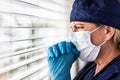 Prayerful Stressed Female Doctor or Nurse Crying At Window Wearing Medical Face Mask Royalty Free Stock Photo